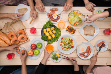 Enjoying dinner with friends.  Top view of group of people having dinner together while sitting at wooden table