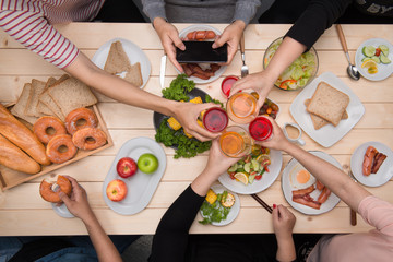 Enjoying dinner with friends.  Top view of group of people having dinner together while sitting at wooden table