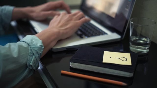 Business man using laptop at home. Sticky note with question sign on desk