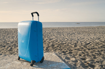A blue suitcase on the beach