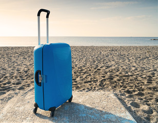 A blue suitcase on the beach