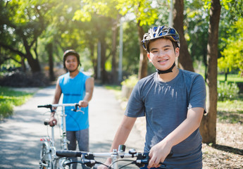 Fototapeta na wymiar Asian boy with friend ride a bike/bicyle at outdoor green park in summer