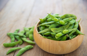 Green beans in wooden cups placed on wooden floor.