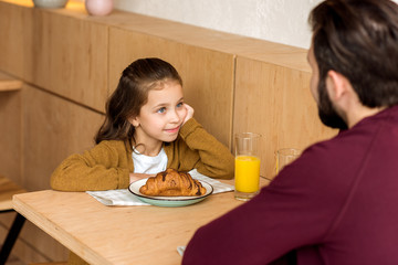 cropped image of daughter looking at father while sitting in cafe