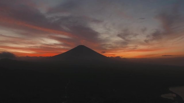 Aerial view of Volcano Mount Agung at sunset with a red orange sky, Bali, Indonesia. Conical volcano of Gunung Agung. mountain landscape. 4K, Aerial footage.