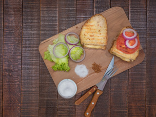 Toasts with melted cheese and vegetables on the board.