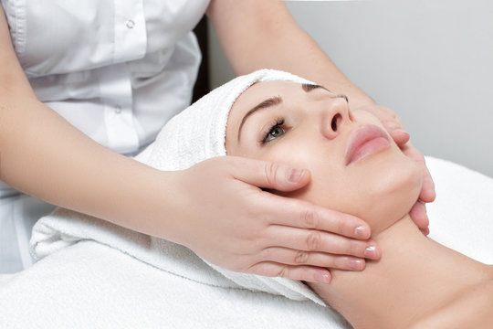 woman receiving facial massage at spa salon