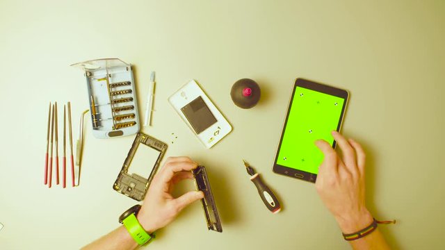 Green screen. Male hands reparing smartphone