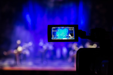 Fototapeta na wymiar Filming the show from the auditorium. LCD viewfinder on the camcorder. Theatrical performance. The actors on stage. Out-of-focus background. The focus in the foreground.