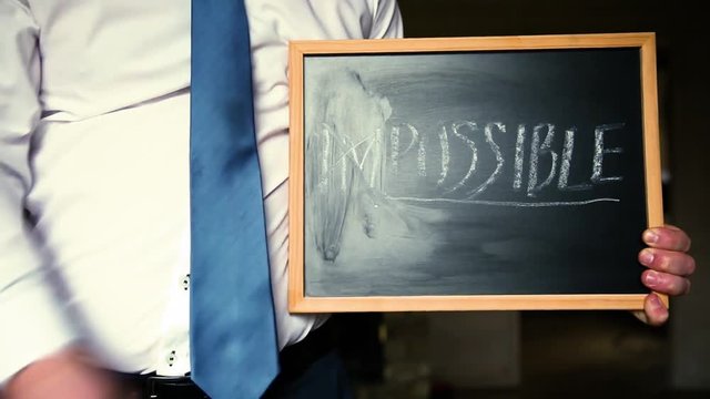 Businessman changing the word impossible to possible. Alphabet I, M being deleted from a chalkboard. Change concept.