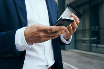 Business man on a break in the city holds a phone and coffee