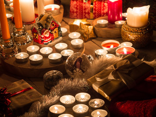 Christmas still life with candles of different size and shape, decorative round wood, souvenir Santa Claus clay house, gift boxes, christmas tree toy.