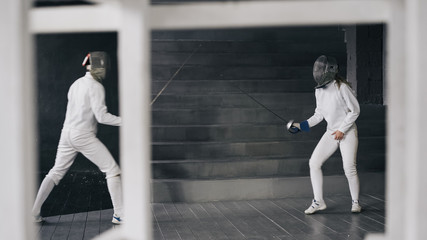 Two fencers man and woman have fencing match indoors