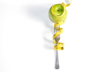 Diet. Apple with Measuring tape wrapped around fork lying ,Healthy eating,weight loss concept on white background