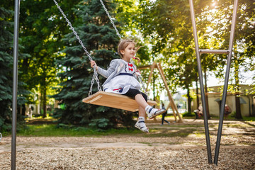 Cute little girl on a swing. Smiling child playing outdoors in summer.