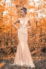 beautiful sensual young brunette bride in long white wedding dress and veil standing in forest