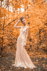 Obraz na płótnie Canvas beautiful sensual young brunette bride in long white wedding dress and veil standing in forest
