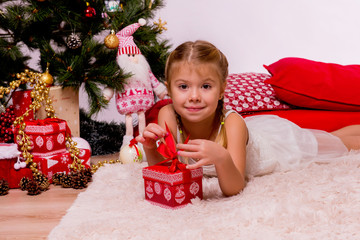 Cute little girl with her festive gift near Christmas tree