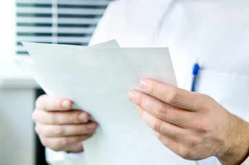 Doctor reading patient's medical record from paper in hospital. Pharmacist with prescription.