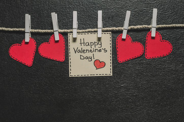 Cut out of red paper hearts hang on the rope on the little primako, greetings happy Valentine's day, top view