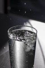 Sprudel Wasser in einem klaren Glas, Wassertropfen springen, prickelnd