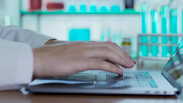 The doctor in the lab typing on notebook report on his research