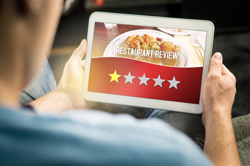 Bad restaurant review. Disappointed and dissatisfied customer giving terrible rating with tablet on an imaginary criticism site, application or website. Man giving one out of five stars at home.