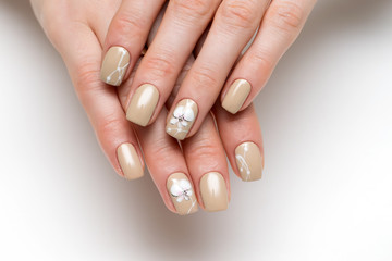 cream, beige manicure on square short nails with painted white orchids on a white background 

