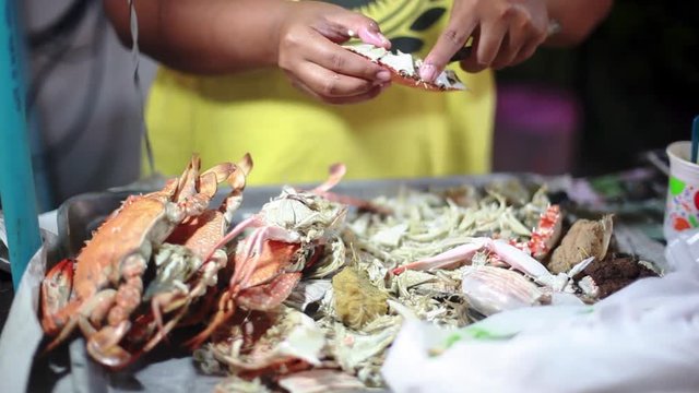 Woman breaks up a cooked crab on night market for sale. 1920x1080