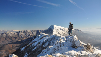 Lonely mountaineer get rest on snowy mountain high above the clouds into the sun
