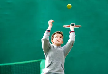 Foto op Canvas Little tennis player on a blurred green background © Stratos Giannikos