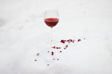 A glass of red wine on white snow