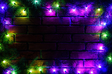 Wreath and garlands of colored light bulbs.Christmas background with lights and free text space. Christmas lights border. Glowing colorful Christmas lights on a brick wall background. New Year.