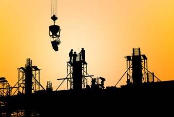 silhouette construction team working on high ground over blurred background sunset sky.