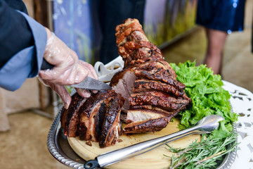Pork knuckle in the hands of the chef cook. Hot dish on the kitchen table close-up.