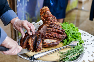 Pork knuckle in the hands of the chef cook. Hot dish on the kitchen table close-up.