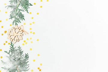 Christmas concept. Fir branches and wooden decoration with golden confetti on white background. Flat lay, top view