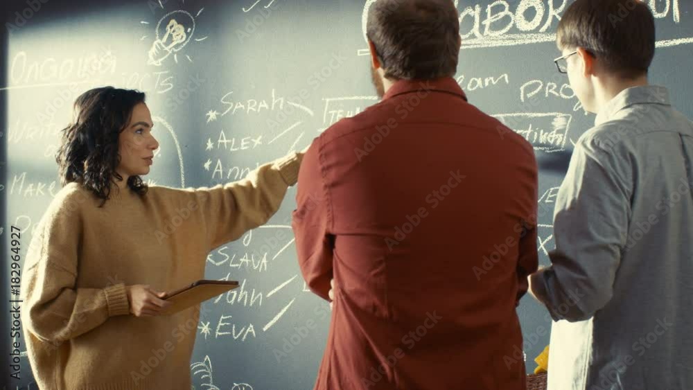 Poster Female Developer with Tablet Computer Talks With Programer and Project Manager, They use Blackboard Wall as a Planner. Shot on RED EPIC-W 8K Helium Cinema Camera.