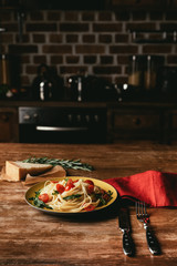 pasta with tomatoes and arugula in plate on table with Parmesan and rosemary