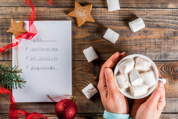 Christmas, New Year concept. Wooden table, notebook with to do list , girl hands holds cocoa mug,...