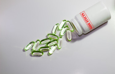 pills on a white background and a bottle with the rubber stamp word side effects