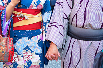 Couple in traditional Japanese kimono walking at temple with sunset in Kyoto, Japan	