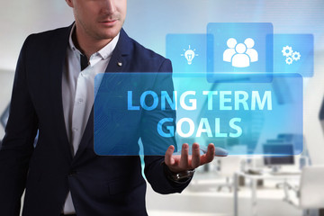 Business, Technology, Internet and network concept. Young businessman working on a virtual screen of the future and sees the inscription: Long term goals