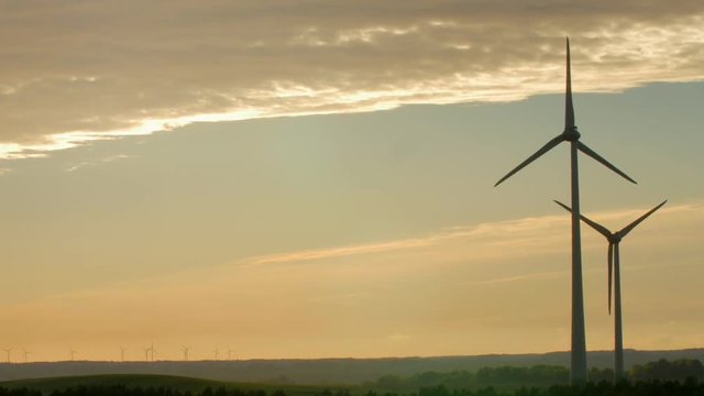 Wind turbine farm with rays of light at sunset, Europe.