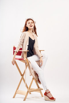 Young beautiful woman on white isolated background sits on a high chair, style, fashion, beauty