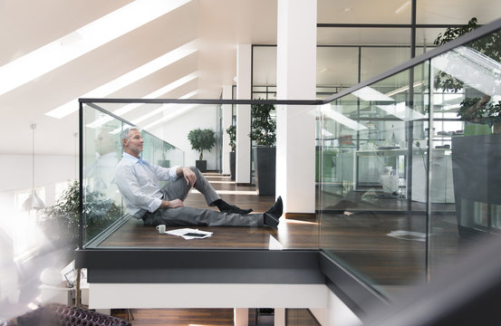 Businessman sitting on floor in the office, taking a break