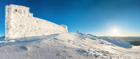 Panorama with man on the top of the winter mountain in snow at sunset