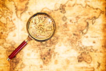 Old map with an magnifying glass exploring it. Vintage travel background