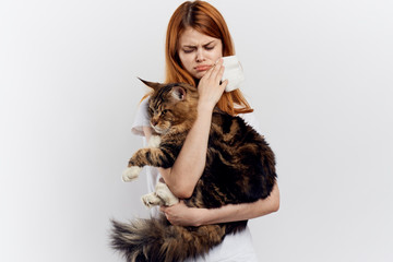 Young beautiful woman on a white background holds a cat, an allergy to pets