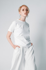 Portraits of a beautiful girl with a short hairstyle on a white background in a white T-shirt